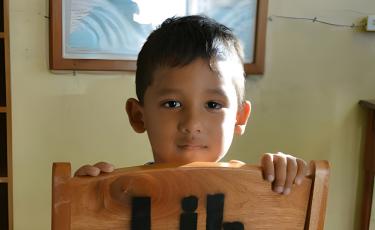 young child holding chair
